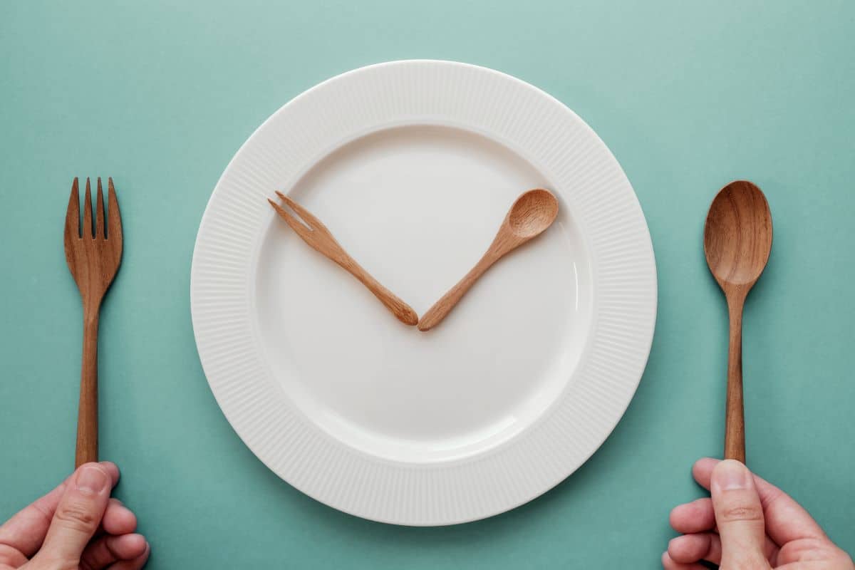 Intermittentent fasting, wooden spoon and fork as a clock hands on a white plate