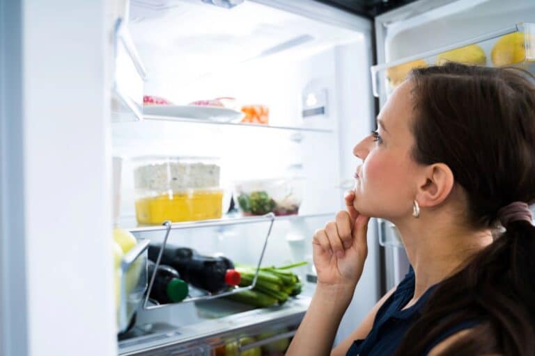 Woman looking into her fridge struggling with brain fog