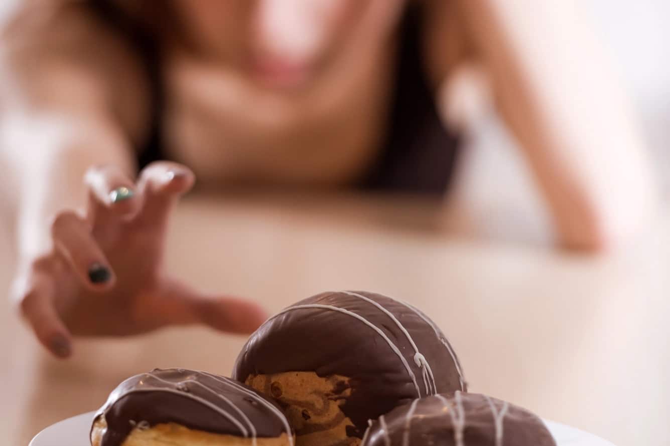 Woman reaching for sweet treats-emotional eating in menopause